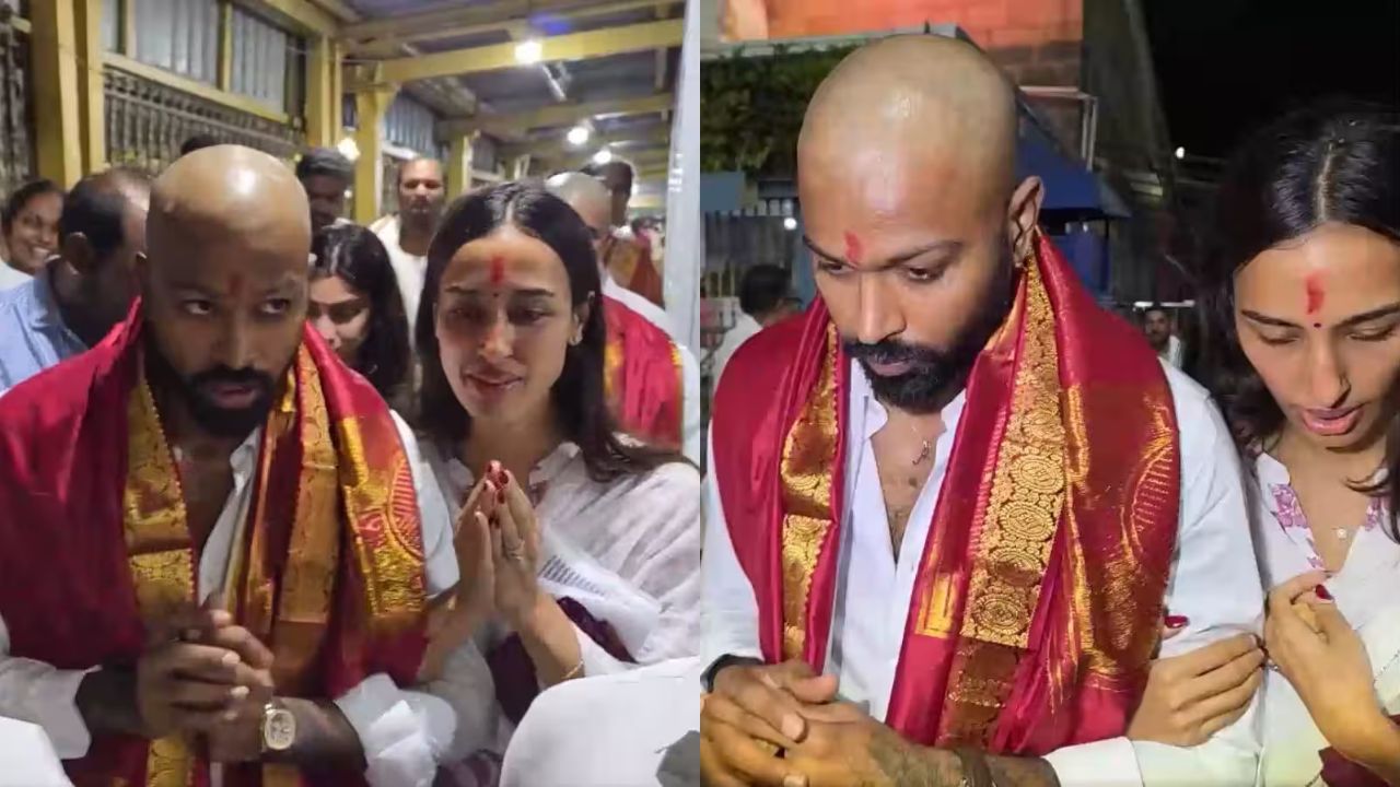 A Hindu wedding scene with two grooms wearing white outfits and gold-embroidered red shawls, praying as guests stand nearby.