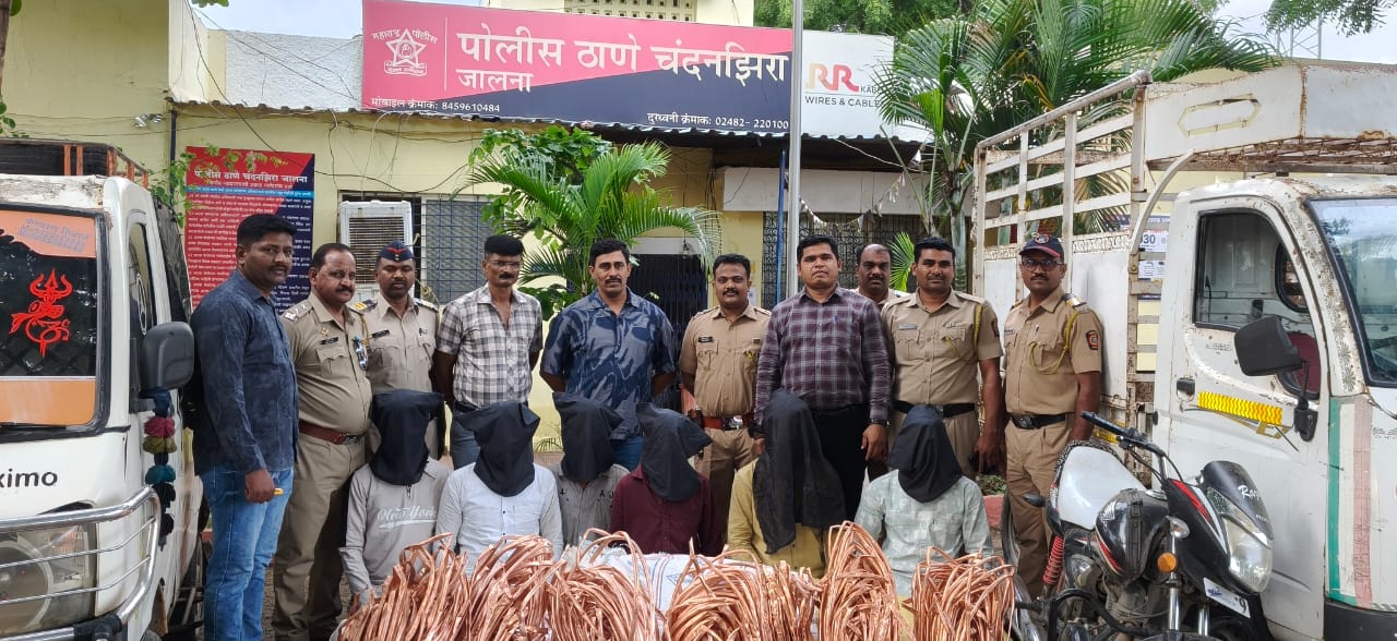 IMG-20260902-WA0018 - NewsNation Online Police officers pose with hooded detainees and large piles of copper wires in front of a police station, flanked by two trucks.