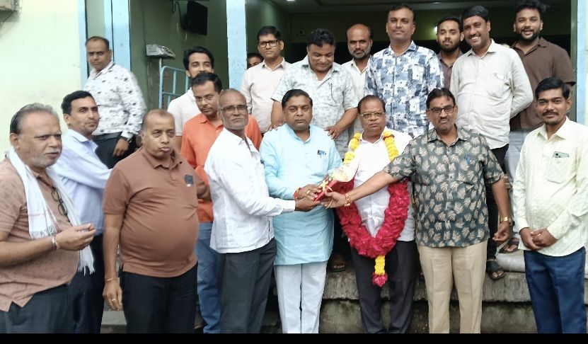 img-20260902-wa00055468657988917413455 - NewsNation Online Group of men posing outside a building as one man with a flower garland is welcomed by colleagues in a ceremony.